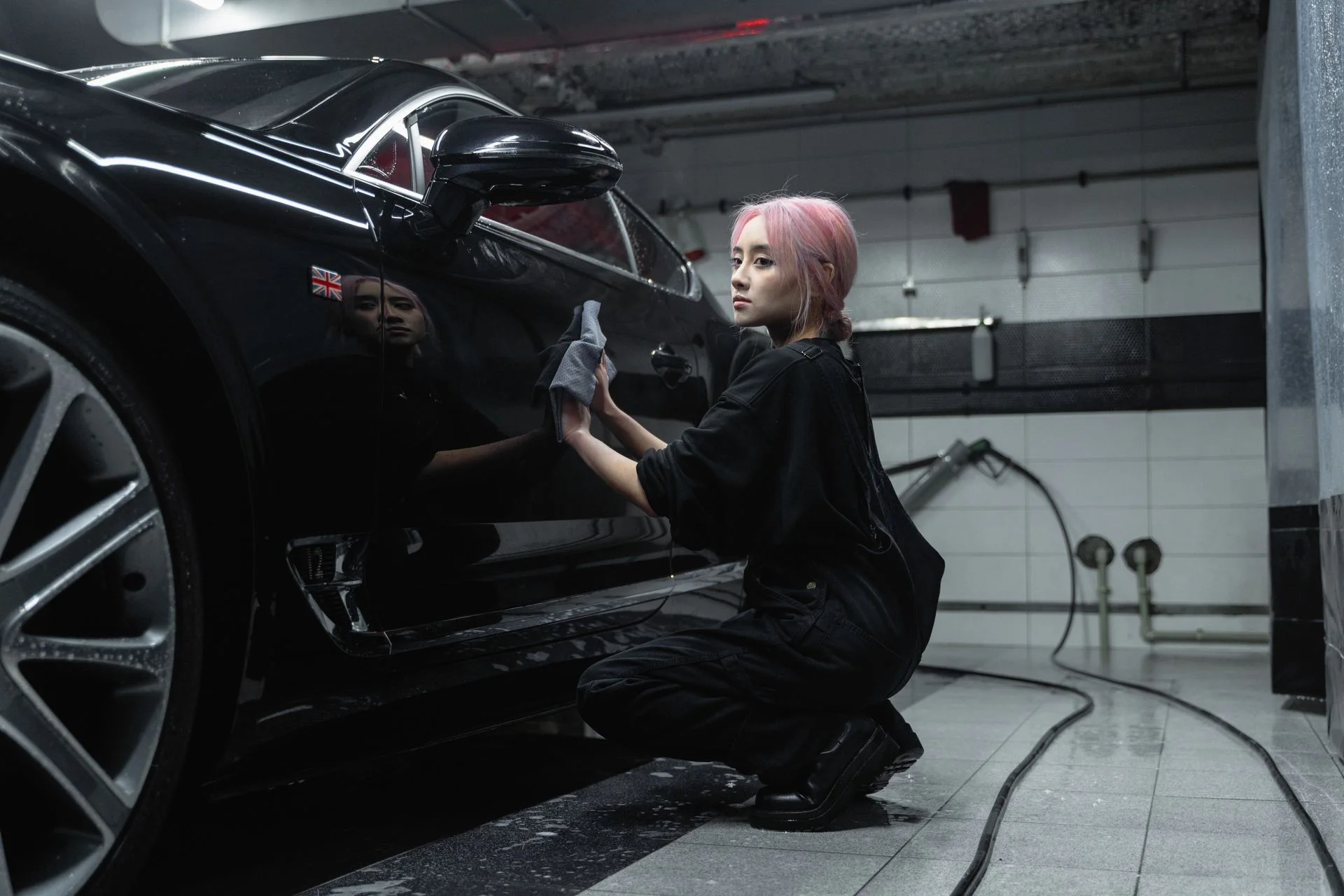 A technician carefully wiping the side of a black car